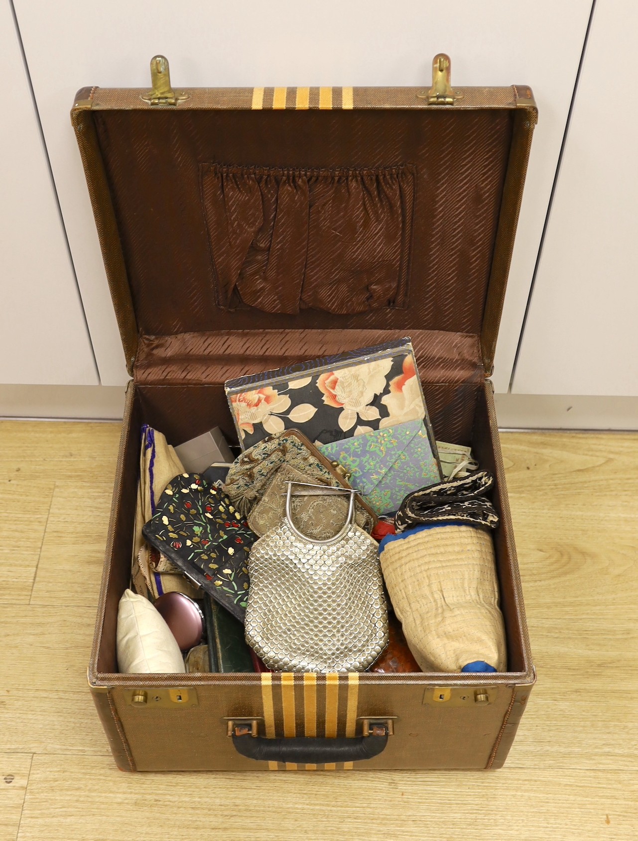 A suitcase containing a collection of late 19th century leather sewing bags and containers, wooden darning mushrooms, etc